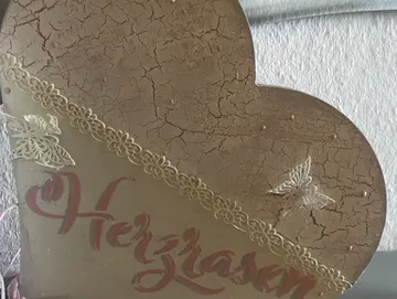 Herzförmige Dekoration mit Schmetterling und „Herzlassen“ -Text.