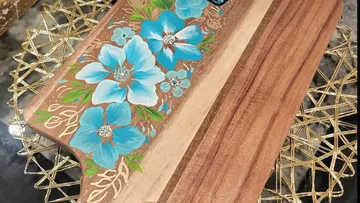 Holzschneidebrett mit bemalten blauen Blumen.