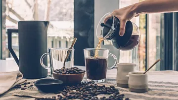 Kaffee von Hand in eine Tasse auf dem Tisch gießen.