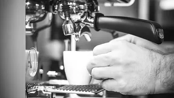 Hands preparing coffee with espresso machine.