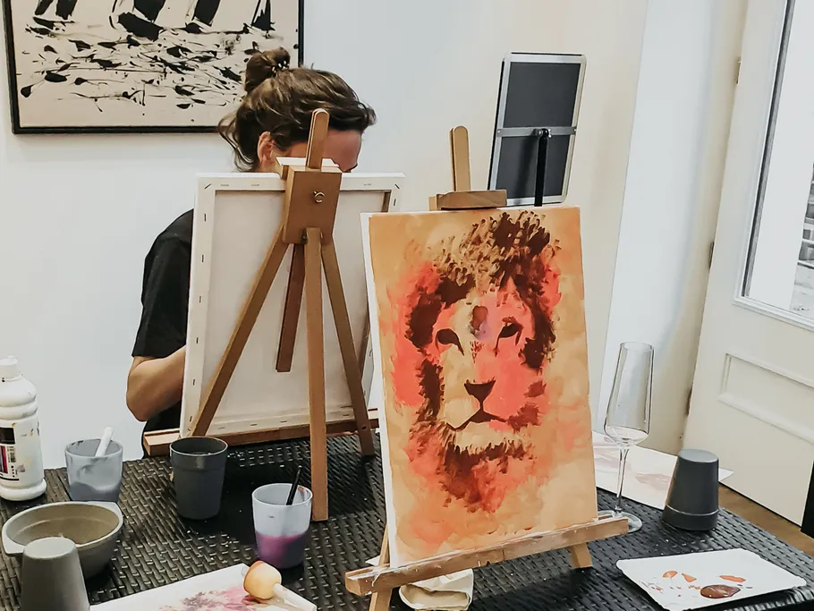 Person painting a lion on canvas indoors.