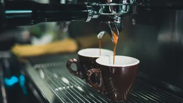 Espressomaschine, die zwei Kaffees in Tassen zubereitet.