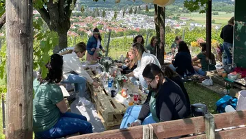 Die Gruppe genießt ein Picknick am Hang mit Tisch.