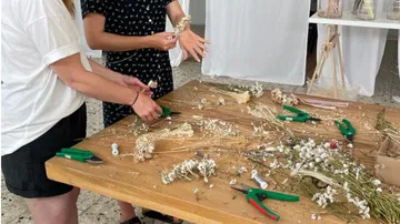 Zwei Personen arrangieren Trockenblumen auf dem Tisch.