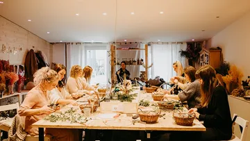 People crafting wreaths in a cozy workshop.