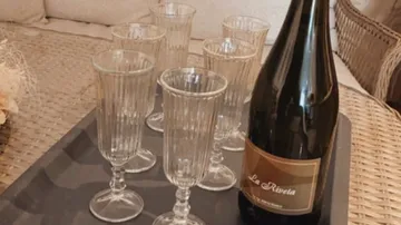 Bottle and six glasses on a tray.