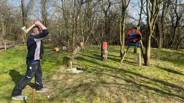 Person, die draußen eine Axt auf ein Zielbrett wirft.