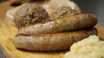 Würste und Fleischbällchen auf Holzbrett.