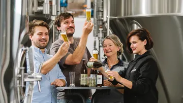 Gruppe, die Bier in einer Brauerei verkostet.