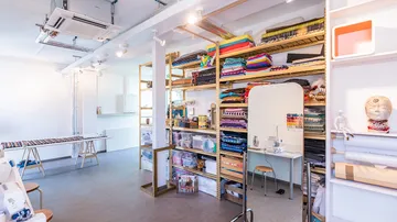 Sewing studio with fabric shelves and sewing machines.