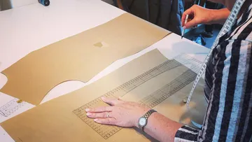 Person marking sewing pattern with ruler.