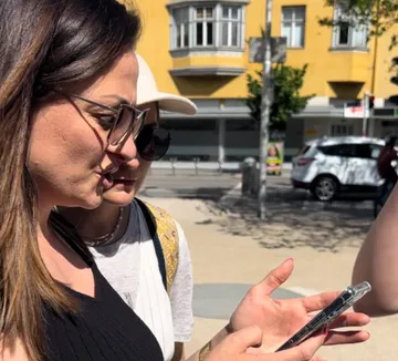 Zwei Frauen schauen auf ein Telefon auf einer sonnigen Straße.