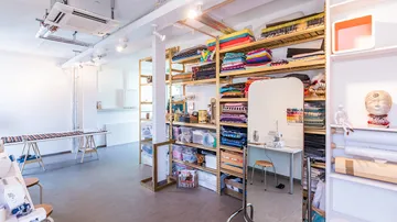 Nähstudio mit Stoffregalen und Maschinen.