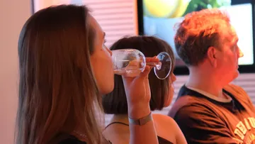 Woman drinking wine in a social gathering.