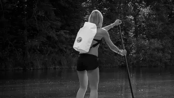 Frau paddelt auf einem ruhigen Fluss.