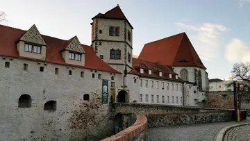 Historic castle with red roofs and tower.