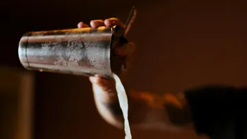 Hand pours liquid from shaker cup