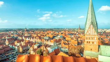Aerial view of Lübeck with red rooftops and church spire.