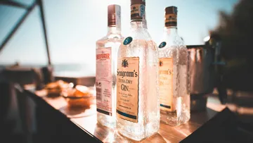 Bottles of gin on outdoor table in sunlight.