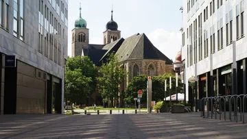 Historic church between modern buildings, sunny day.