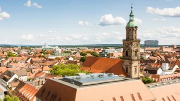 Historic church tower in a cityscape under blue sky.