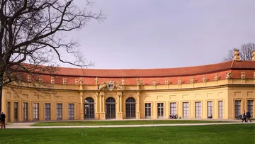 Baroque building with curved facade and red roof.