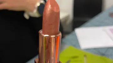 Copper lipstick in focus, blurred background.