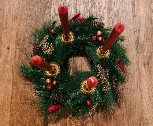 Weihnachtskranz mit roten Kerzen auf Holz.