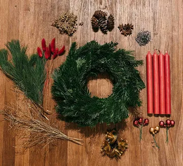 Materialien zur Herstellung von Weihnachtskränzen auf einem Holztisch.