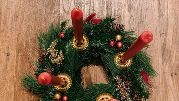 Adventskranz mit roten Kerzen auf dem Tisch.