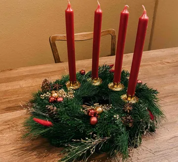 Adventskranz mit vier roten Kerzen auf dem Tisch.