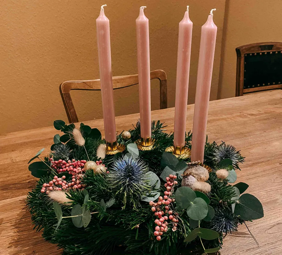 Adventskranz mit rosa Kerzen auf dem Tisch.
