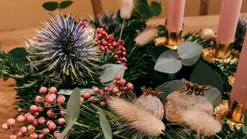 Festive wreath with purple thistle, berries, and candles.