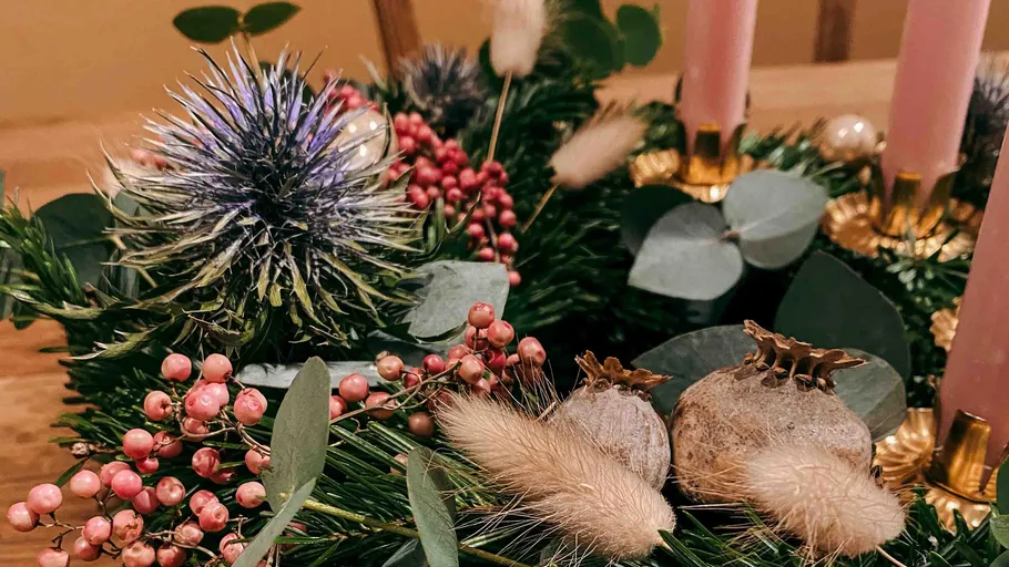 Festive wreath with purple thistle, berries, and candles.
