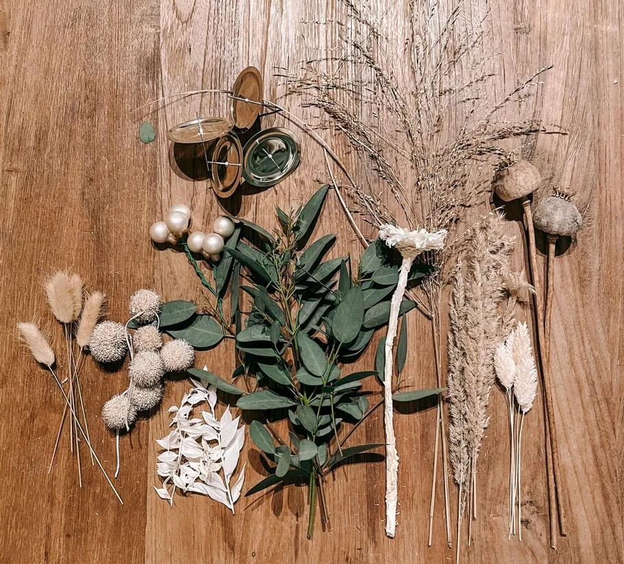 Dried flowers and green foliage on wood table.