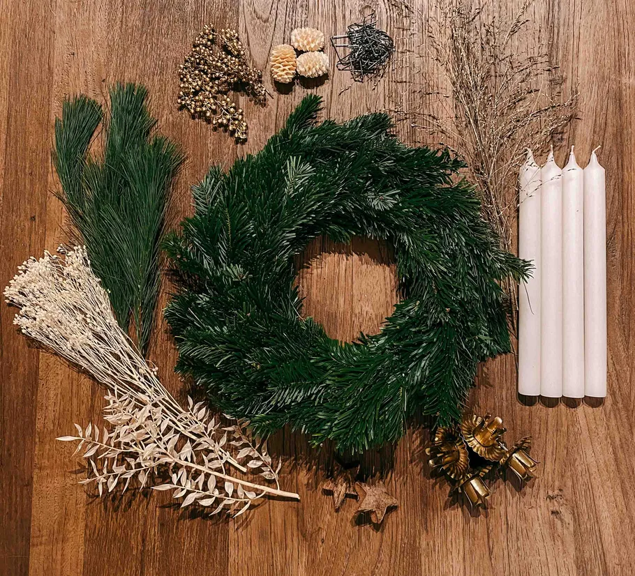 Materialien für Weihnachtskränze, auf einem Holztisch angeordnet.