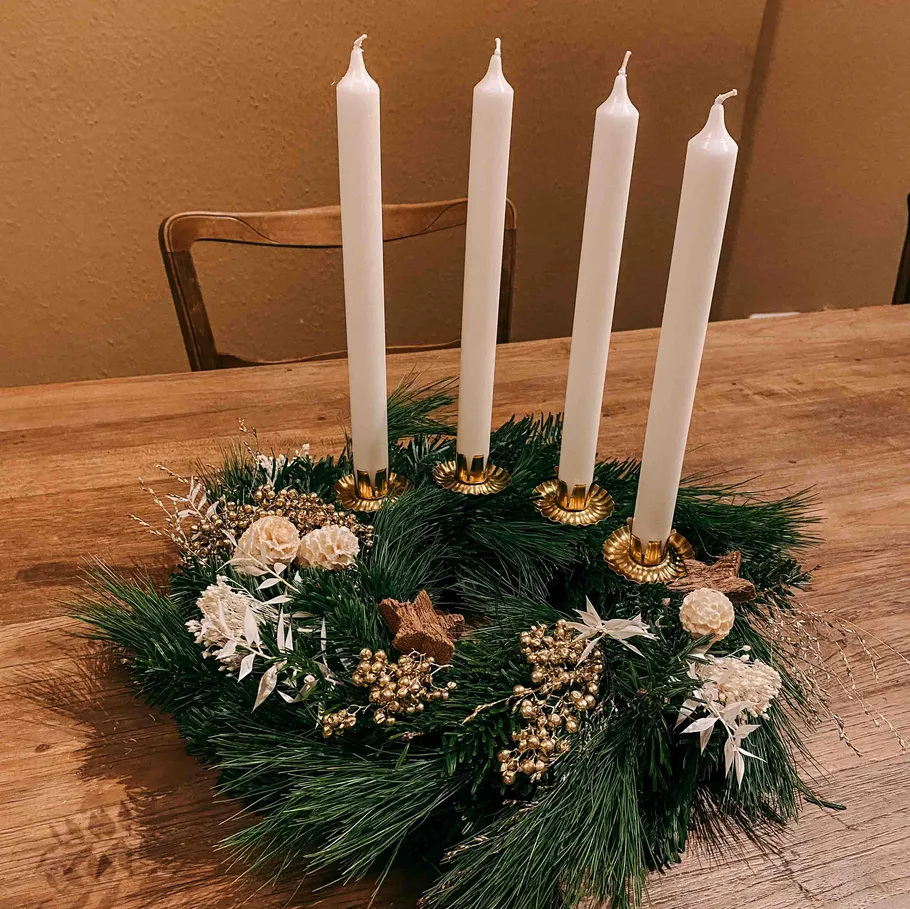 Vier weiße Kerzen im Herzstück aus Kiefernkranz.