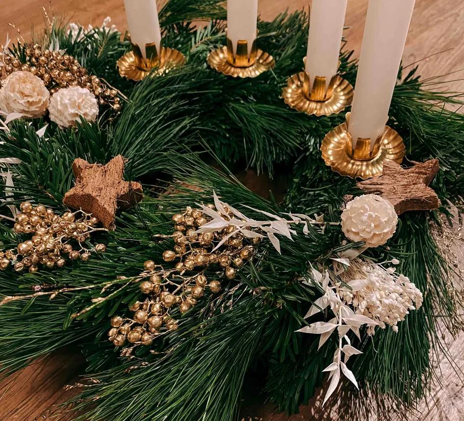 Decorative pine wreath with candles and gold accents.