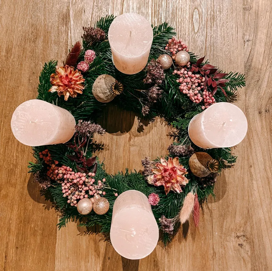 Decorative wreath with candles on wood table.