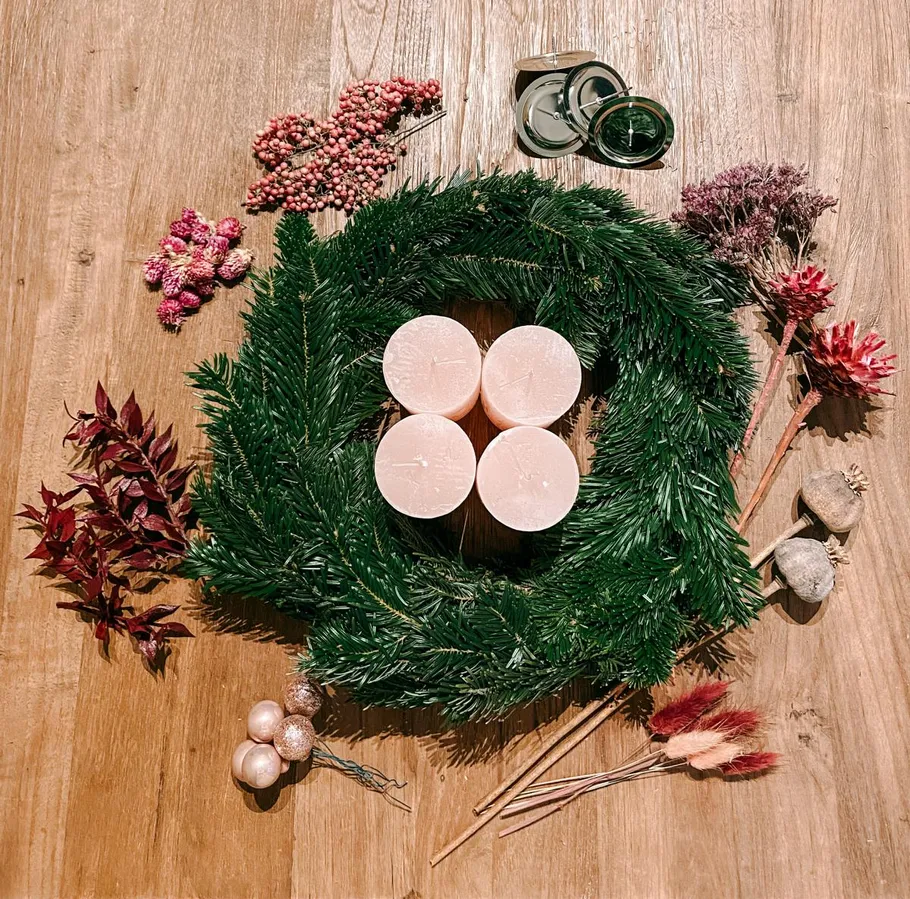 Green wreath with candles and decorations on table.