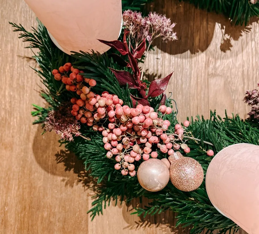 Festlicher Kranz mit rosa Kerzen und Beeren