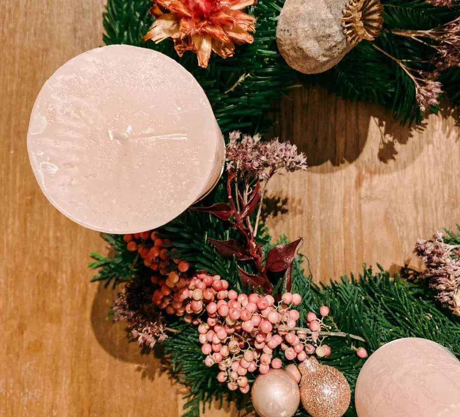Candle on decorative wreath with pine and berries.