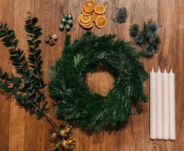 Materialien zur Herstellung von Weihnachtskränzen auf einem Holztisch.