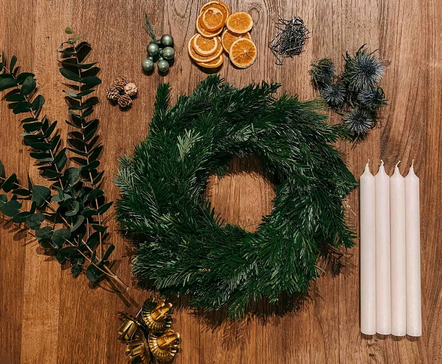 Christmas wreath-making materials on wooden table.