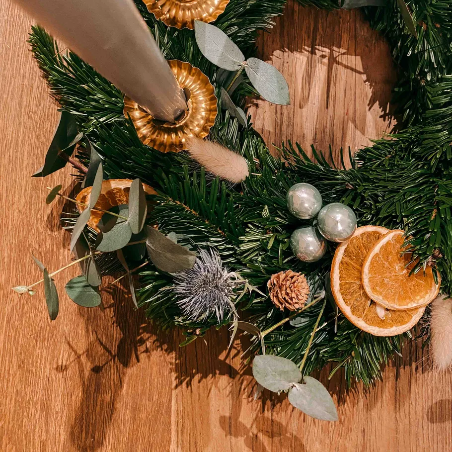 Christmas wreath with oranges and candle on wood.