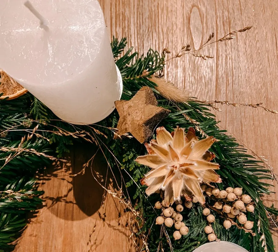 White candle on decorative wreath on table.