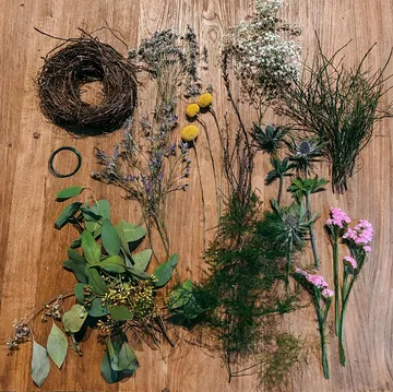Verschiedene Trockenblumen und Bindfaden auf Holztisch.