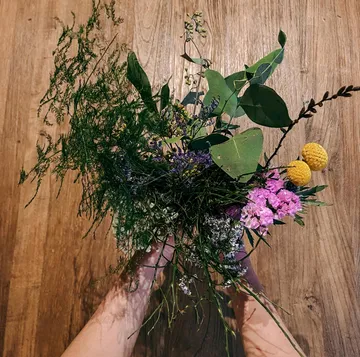 Hands holding a colorful flower bouquet.