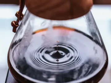 Eine Kanne mit Wasser erzeugt Wellen durch einen Tropfen.