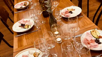 Wooden table set with plates and wine glasses.